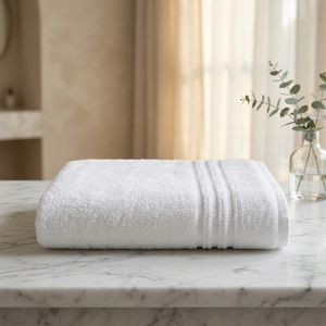 A folded white cotton towel with ribbed trim sits on a white marble countertop